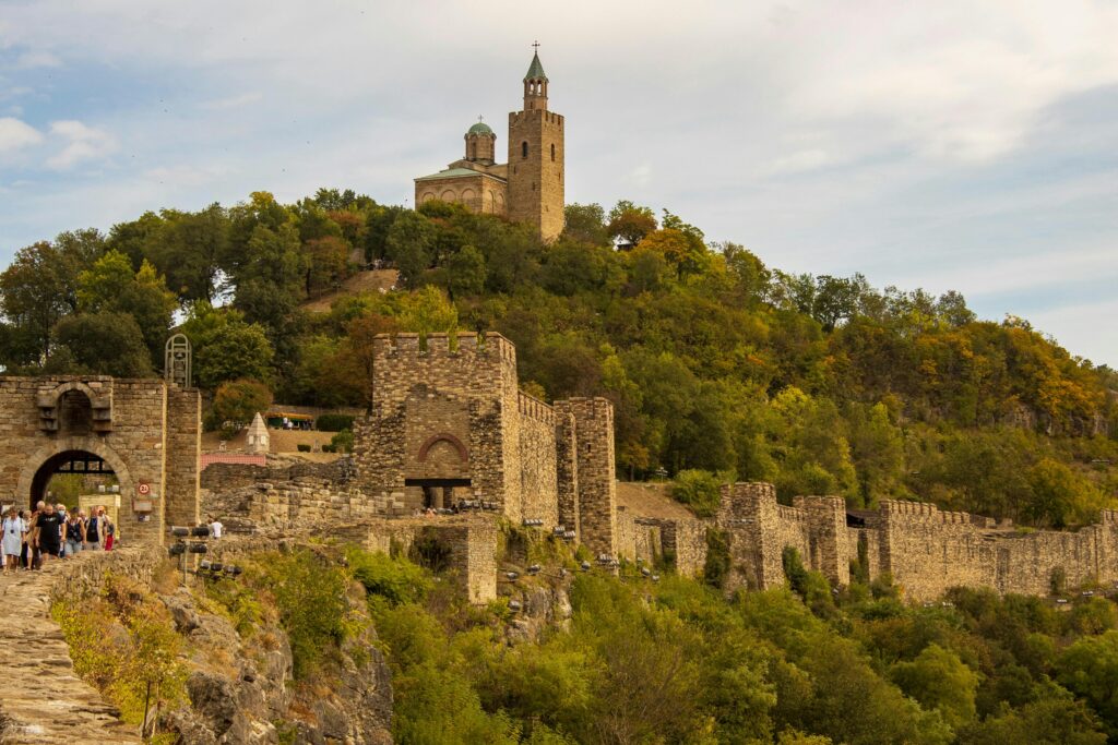 הטיולים שלנו Tsarevets Fortress in Bulgaria amidst green hills, a scenic view of historical architecture.